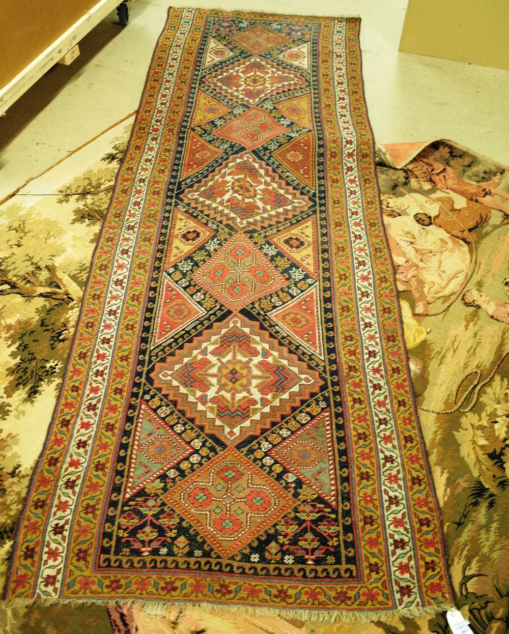 A Persian tribal runner with seven medallions within polychrome borders,