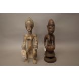 An African tribal female figure modelled seated and holding an umbrella,
