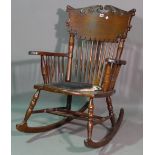 A late 19th century oak American rocking open armchair, with spindle back and turned supports.