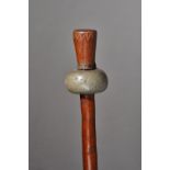 A New Britain mace club, the ovoid stone head on a carved tapering cylindrical shaft, 135cm.