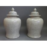 A pair of modern Chinese pottery vases and covers decorated with crackle glaze against a baluster