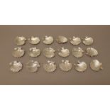 Eighteen small dishes modelled as scallop shells, each fitted with a hook,