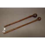Two East African hardwood clubs, each with bulbous head and tapering cylindrical handle,