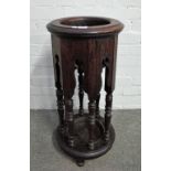 An early 20th century oak circular stick stand with arch frieze and baluster turned supports,