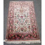 A small Persian part silk rug, white ground with bird and floral decoration around a vase,