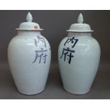 A pair of modern Chinese pottery vases and covers decorated with blue script against a white ground,