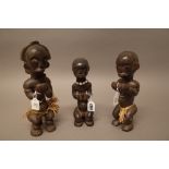 Three Fang carved wooden reliquary figures with straw and shell decoration, 25cm high, (3).