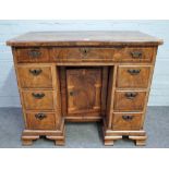 A mid-18th century walnut kneehole writing desk with seven drawers about the recessed cupboard,