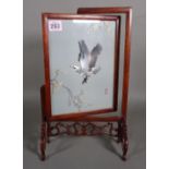 A 20th century Chinese silk work picture, depicting an eagle in flight, within a hardwood stand,