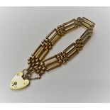 A gold bar and oval link gate bracelet, on a gold heart shaped padlock clasp, detailed 9 CT GOLD,