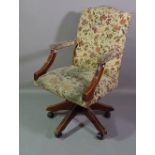 A 20th century mahogany framed hump back office open armchair with floral upholstery.