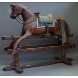 An early 20th century stained pine rocking horse on a wrought iron and stained pine swing frame