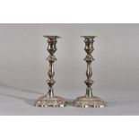 A pair of silver table candlesticks, each having a knopped stem and raised on a shaped square base,