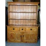 An early 20th century pine dresser with three tier plate rack over three drawer cupboard base,