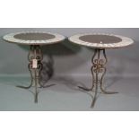 A pair of 20th century wrought iron and stone circular garden tables on outswept supports,
