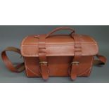 A heavy leather and brass mounted travel bag with buckle and strap fastening and adjustable
