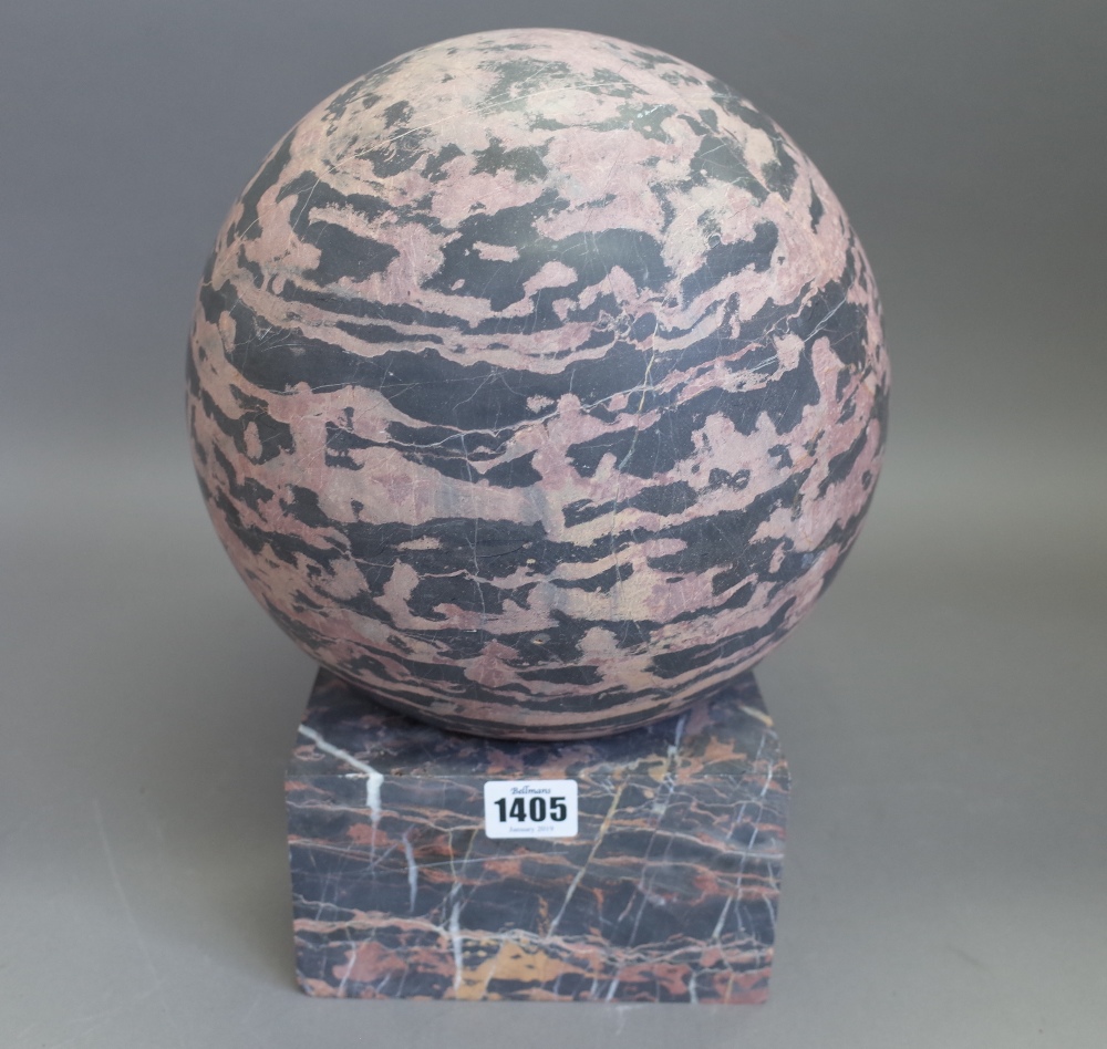 A black/red marble sphere or pier finial on a dished square stand, sphere 24cm diameter.