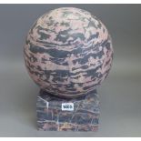 A black/red marble sphere or pier finial on a dished square stand, sphere 24cm diameter.