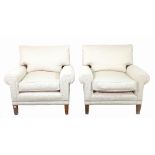 A pair of low armchairs with studded white cotton upholstery on tapering supports,