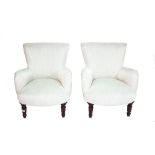 A pair of hardwood framed low armchairs with white upholstery on ebonised turned supports,
