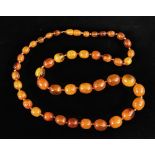 An amber type single row necklace of graduated oval beads, approx. 76cm long overall.