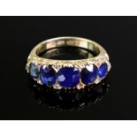 A late Victorian gold and sapphire five stone carved half-hoop ring with rose diamond points,