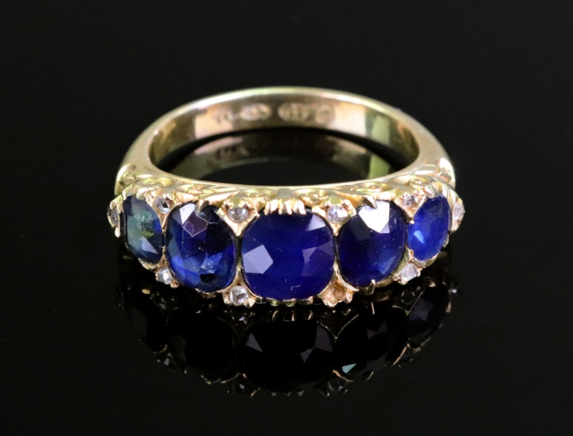 A late Victorian gold and sapphire five stone carved half-hoop ring with rose diamond points,