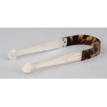 A pair of George III tortoiseshell mounted carved mother of pearl sugar tongs, of silver shape,