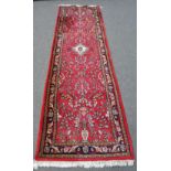 A Hamadan runner, the madder field with an ivory medallion, all with floral sprays,