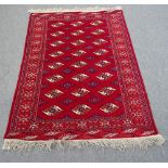 A Turkman rug, the madder field with three columns of eight guls, a sunburst border, skirt ends,