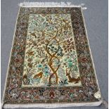 A silk Ghom tree of life rug, Persian, the ivory field with entwined trees, with birds, flowers,