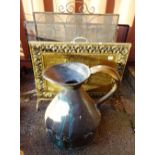 An embossed brass fire screen 58cm wide, two wrought iron and mesh fire guards and a copper jug,