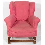 A 20th century pink upholstered wing armchair with cabriole supports and perimeter stretcher.