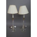 A pair of modern glass candlestick table lamps, each with cream pleated shades, 65cm high.