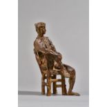 A patinated bronze figure, of abstract form, modelled seated in a chair,