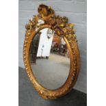 A mid-19th century gilt framed mirror, with opposing cherub crest above oval plate,