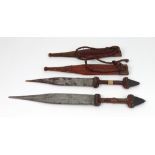 Two West African daggers, with steel blades, leather and snakeskin covered handles and scabbards,