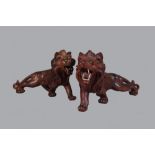 A pair of Asian carved hardwood animalier figures of prowling lions, glass inset eyes, 25cm long,