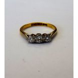 A gold and platinum, diamond set three stone ring, mounted with a row of circular cut diamonds,