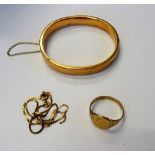 A gold oval hinged bangle, detailed 15 CT, on a snap clasp, fitted with a safety chain,