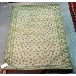 An ivory and green machine made rug, 181cm x 122cm.