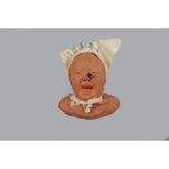 GD Paris; a novelty terracotta pincushion in the form of a crying child, white linen cap,