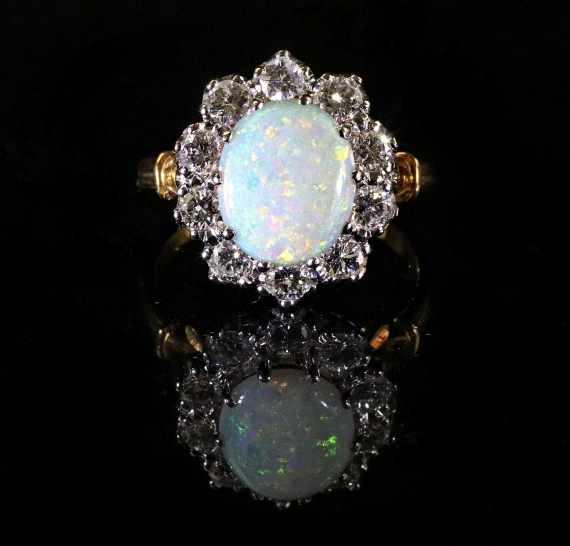 A gold, opal and diamond cluster ring, mounted with the oval opal at the centre,