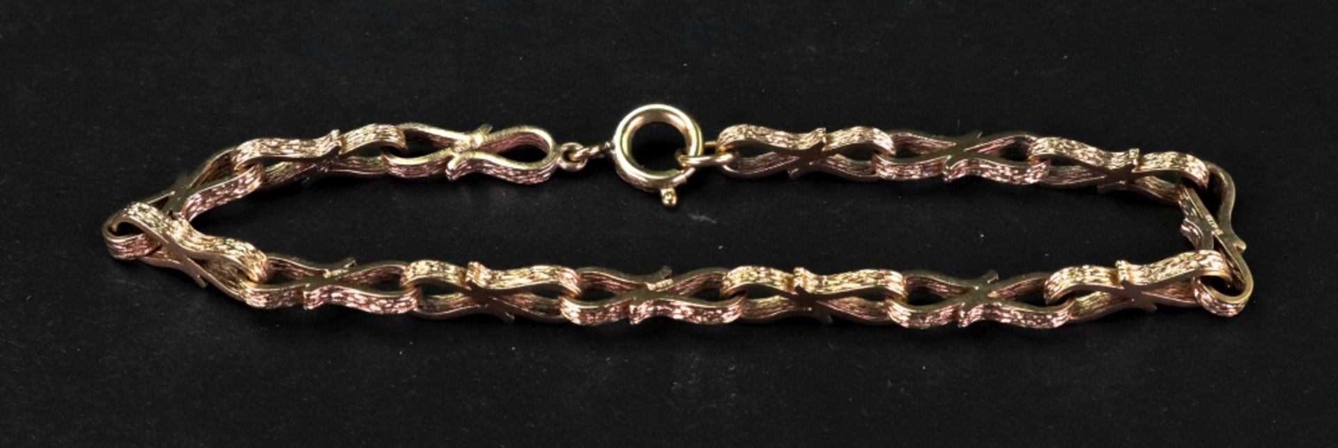 A gold fancy link bracelet, the links mounted at alternate angles with textured finish,