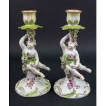A pair of Derby porcelain candlesticks, circa 1760, each modelled as a putto holding a cup,