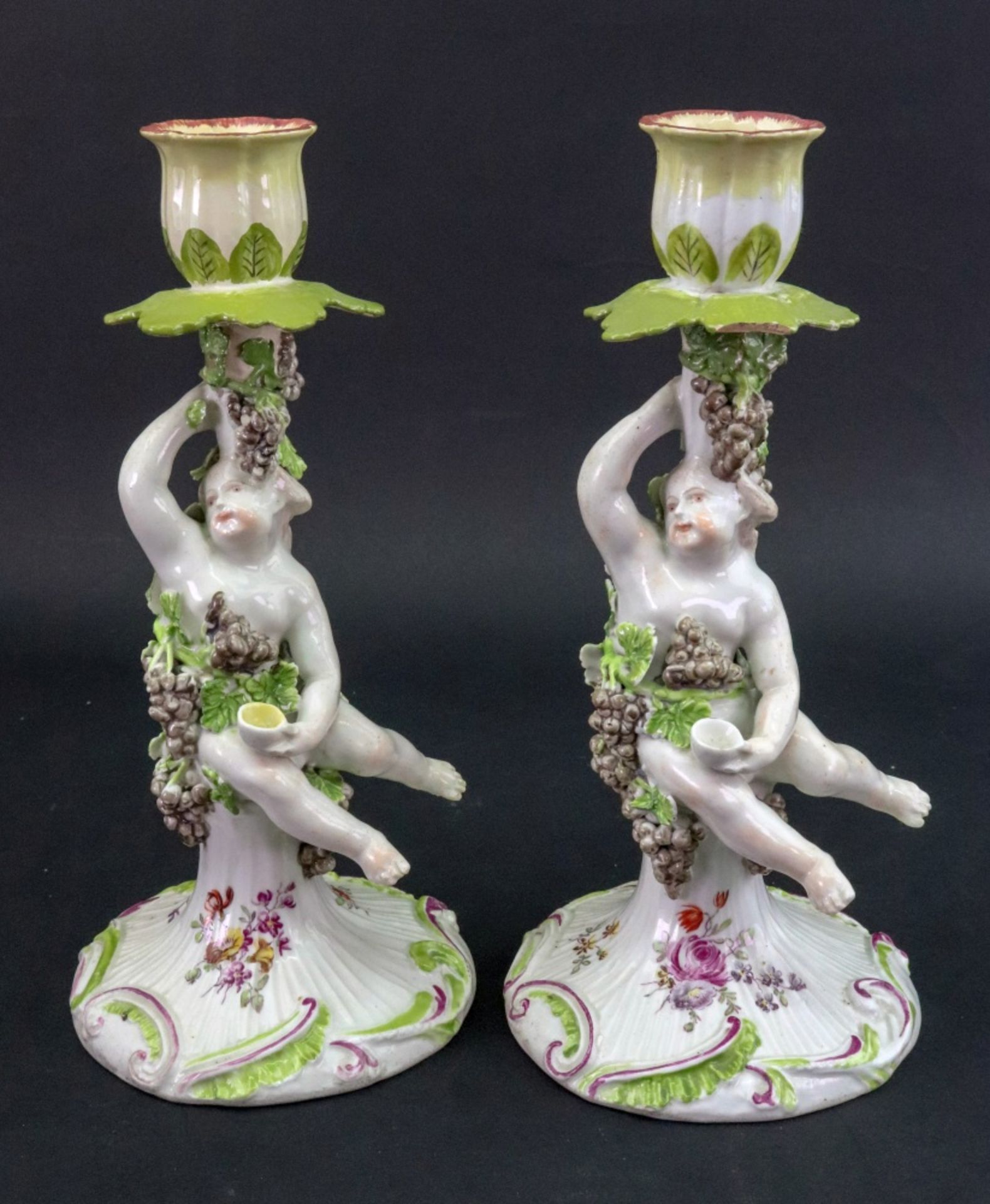 A pair of Derby porcelain candlesticks, circa 1760, each modelled as a putto holding a cup,