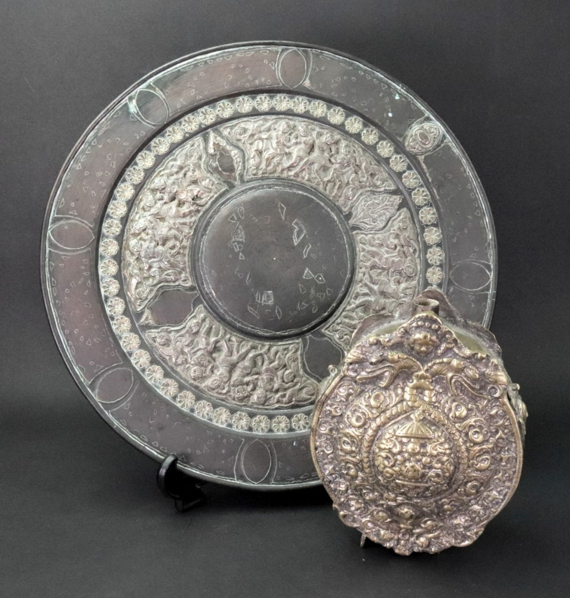 An Eastern metal plate, decorated with figures and a repeated flower head design, 30.