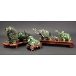 A group of Chinese green hardstone figures, 20th century, comprising:- a family of three elephants,