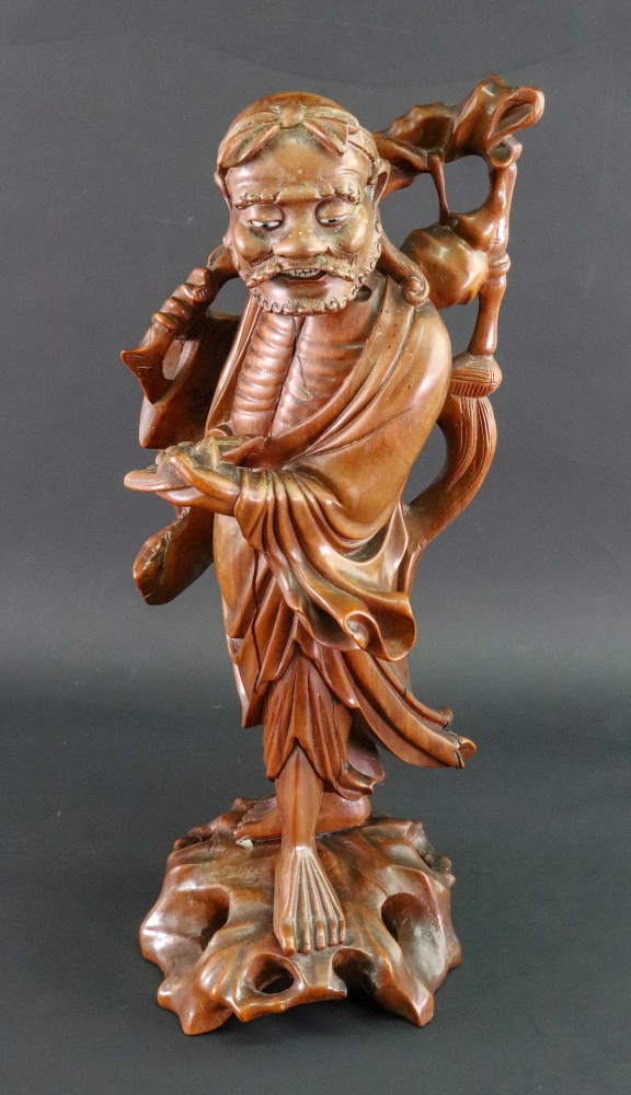 A Chinese carved wood figure of a man carrying a branch over his shoulder, 20th century, 38cm high.