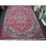 A Kerman carpet, Persian, the madder field with a bold black and pale indigo medallion,